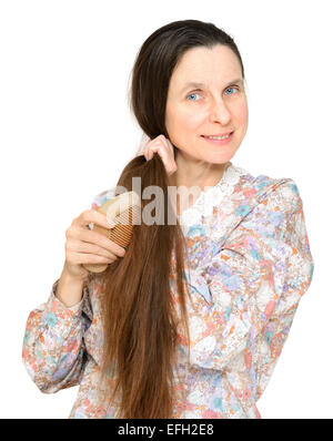 Donna adulta pettinare capelli lunghi marrone con un pettine di legno, isolato su sfondo bianco Foto Stock