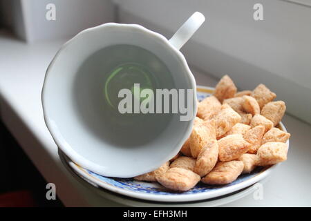 Bianco vuoto profondo tazza di porcellana giaceva su un lato del piattino con snack dolce Foto Stock