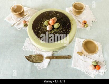 Torta di Pasqua con tè corrispondono a uova di cioccolato decorate. Vicino a tazza di caffè. A partire dalla serie elegante dessert Foto Stock