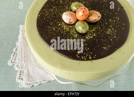 Torta di Pasqua con tè match decorate ganache al cioccolato e dolce-stuff uova. Vicino a tazza di caffè. A partire dalla serie elegante dessert Foto Stock