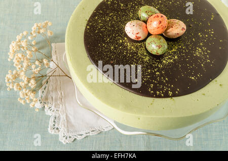 Torta di Pasqua con tè match decorate ganache al cioccolato e dolce-stuff uova. Vicino a tazza di caffè. A partire dalla serie elegante dessert Foto Stock