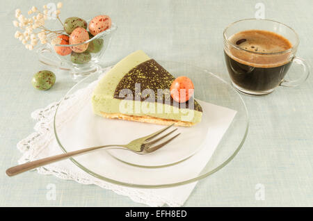 Pezzo di torta di Pasqua con tè match decorate ganache al cioccolato e dolce-stuff le uova sulla lastra di vetro. A partire dalla serie elegante dessert Foto Stock