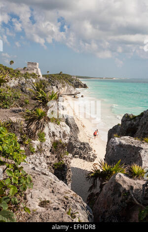 A piedi le rovine di Tulum Beach. Un giovane cammina da sola lungo la spiaggia che sarà presto affollata di bagnanti, il sole e l'acqua. Foto Stock