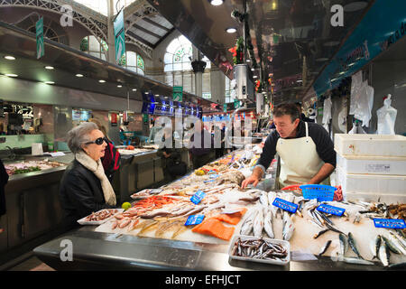 Commerciante di mercato la selezione di pesce per un cliente nel mercato centrale di Valencia Foto Stock