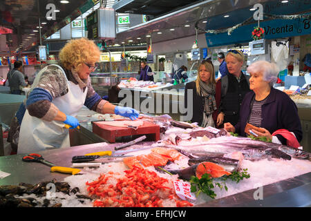 Commerciante di mercato la sfilettatura pesce per un cliente nel mercato centrale di Valencia Foto Stock