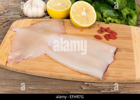 Materie squid su un tagliere sul tavolo da vecchie schede madri Foto Stock