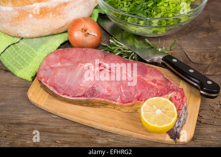 Bistecca di crudo pesce gatto su un tagliere sul vecchio tavolo in legno Foto Stock