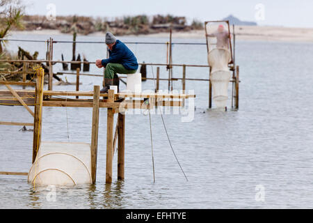 Pescatore seduto su un cavalletto di bianchetti, Whitebaiting presso la foce, West Coast, Isola del Sud, Nuova Zelanda Foto Stock