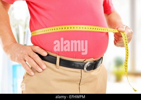 Close-up su un uomo misurando il suo ventre a casa Foto Stock