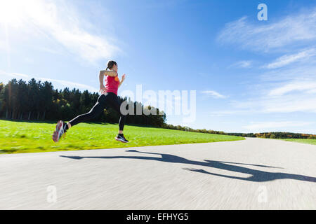 Donna jogging lungo una strada, Munsing, Baviera, Germania Foto Stock