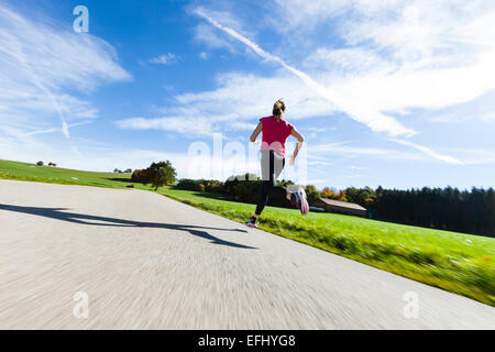 Donna jogging lungo una strada, Munsing, Baviera, Germania Foto Stock