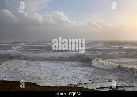 Molto ruvida mari invernali in Bideford Bay off Saunton, North Devon, Inghilterra, Regno Unito, con grandi onde cresta soleggiato nel tardo pomeriggio Foto Stock