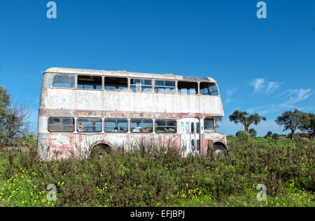 Rusty abbandonate Bus Double-Decker in piedi in un campo, un giorno di sole Foto Stock