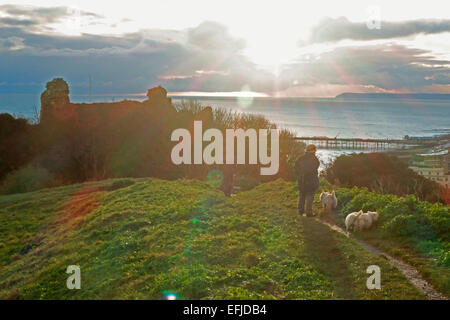 Hastings, East Sussex, 5 feb 2015. Dog walkers sulla Collina del Castello gli ultimi raggi di sole su una fredda sera sulla costa sud. Foto Stock