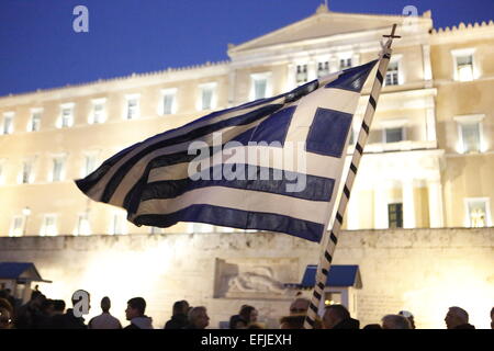 Atene, Grecia. 5 febbraio 2015. Un manifestante sventola una bandiera greca al di fuori del parlamento greco. Migliaia di Greci assemblati a piazza Syntagma, per protestare contro il regime fiscale di estorsione da parte della Troika che vuole che la Grecia a seguire le loro istruzioni in ritorno per fornire il denaro necessario per le banche greche. Credito: Michael Debets/Alamy Live News Foto Stock