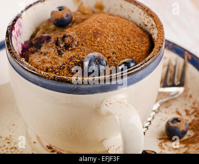 Forno a microonde con muffin ai mirtilli freschi sul tavolo di legno Foto Stock