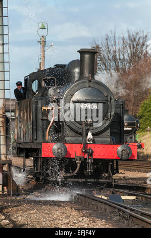 Jinty Classe 3F 0-6-0T steam loco sotto un traboccante water tower per assumere acqua a Loughborough sulla grande stazione ferroviaria centrale Foto Stock