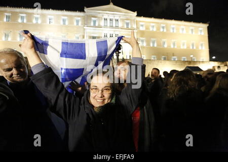 Atene, Grecia. 5 febbraio 2015. Una donna sventola una bandiera greca sulla sua testa al di fuori del parlamento greco. Migliaia di Greci assemblati a piazza Syntagma, per protestare contro il regime fiscale di estorsione da parte della Troika che vuole che la Grecia a seguire le loro istruzioni in ritorno per fornire il denaro necessario per le banche greche. Credito: Michael Debets/Alamy Live News Foto Stock