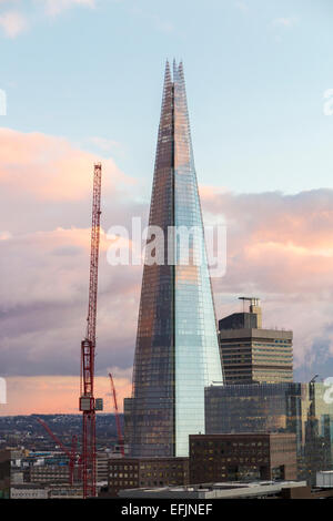 La Shard, London SE1, nella luce della sera con una gru a torre, il tramonto riflettendo nel lato dell'edificio con nuvole rosa Foto Stock