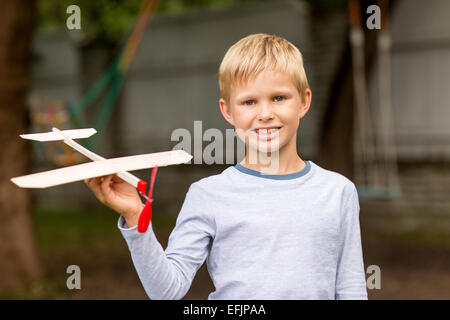 Sorridente ragazzino tenendo un legno modello di aeroplano Foto Stock