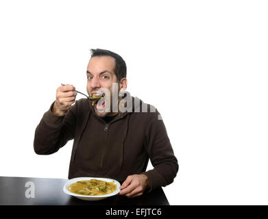 Giovane uomo di mangiare la minestra di verdura con la bocca aperta Foto Stock