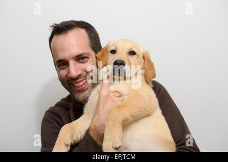 Uomo con giallo Labrador Golden Retriever cucciolo mix Foto Stock