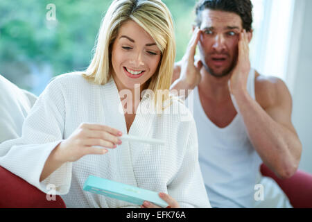 Ragazza felice di scoprire è incinta con sconvolto l uomo in background Foto Stock