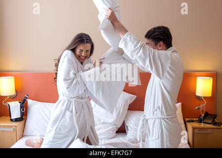 Felice coppia avente Pillow Fight in camera di albergo Foto Stock