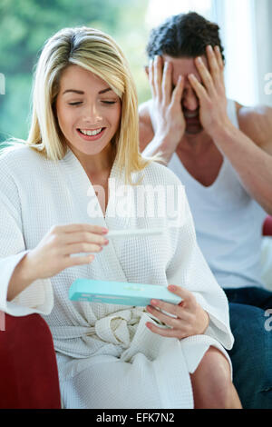 Ragazza felice di scoprire è incinta con sconvolto l uomo in background Foto Stock