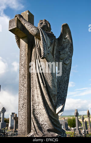 Angelo statua abbracciando una croce e celtic cimitero a Ardmore nella contea di Waterford, Irlanda con aggiunta di grano Foto Stock