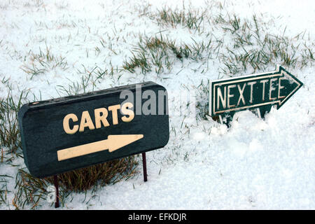 Carrelli e tee successivo segno su una coperta di neve del campo da golf links in Irlanda nel nevoso inverno meteo Foto Stock