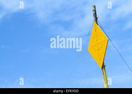 Giallo cavo telefonico segno sul palo del telegrafo contro il cielo blu Foto Stock