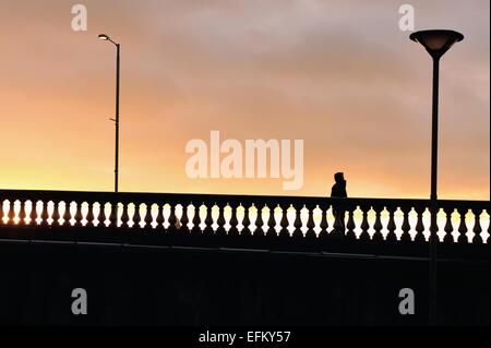 Glasgow, Scotland, Regno Unito. Il 6 febbraio, 2015. Un uomo, cofano sollevato, è silhoutted contro il tramonto sul ponte di Glasgow. Credito: Tony Clerkson/Alamy Live News Foto Stock