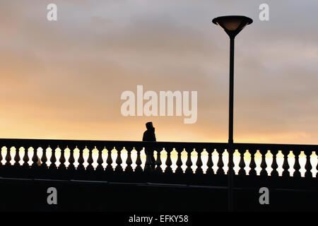 Glasgow, Scotland, Regno Unito. Il 6 febbraio, 2015. Un uomo, cofano sollevato, è silhoutted contro il tramonto sul ponte di Glasgow. Credito: Tony Clerkson/Alamy Live News Foto Stock