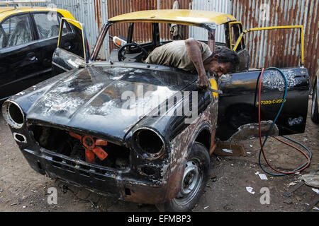 Un meccanico di riparare un vecchio Premier Padmini auto sulla strada in Mumbai, India Foto Stock