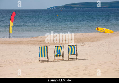 Tre sdraio vuota tra RNLI bagnini della tavola da surf e un marcatore flag a Bournemouth Beach nel giugno Foto Stock