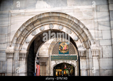 Porta del Grand Bazaar Moschea Nuruosmaniye Istanbul Turchia | ISTANBUL, Turchia — Incorniciato dagli archi del colonnato del cortile della moschea Nuruosmaniye, l'ingresso principale del Grand Bazaar — Porta 1, nota come Nuruosmaniye Kapısı — si trova appena oltre il muro del complesso, una giustapposizione che cattura la tradizione ottomana di collocare complessi di moschee imperiali adiacenti ai principali centri commerciali. La fondazione fu posa nel gennaio 1749 sotto il sultano Mahmud I, e la moschea fu completata e nominata dal sultano Osman III il 5 dicembre 1755. L'architetto greco Simeon Kalfa ha guidato il progetto, rendendo questo il primo grande imper Foto Stock