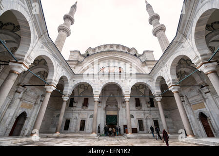 ISTANBUL, Turchia: Il caratteristico cortile a ferro di cavallo della Moschea Nuruosmaniye presenta un innovativo design poliangolare del chiostro unico nell'architettura ottomana. Completato nel 1755, questo colonnato semicircolare rappresenta un drammatico allontanamento dai tradizionali cortili di moschea rettangolari, esemplificando lo stile barocco ottomano. L'insolita forma curva del cortile dimostra la sperimentazione architettonica del periodo. Foto Stock