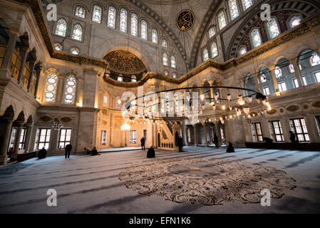 Nuruosmaniye Mosque Prayer Hall Interior Istanbul Turkey // ISTANBUL, Turkey — la sala di preghiera decorata con decorazioni della Moschea Nuruosmaniye mostra lo stile architettonico barocco ottomano emerso nel XVIII secolo. Completata nel 1755 durante il regno del sultano Osman III, la moschea fu la prima moschea imperiale costruita a Istanbul in oltre un secolo e segnò un significativo allontanamento dal design ottomano classico. L'interno presenta un'elaborata calligrafia, intricate incisioni in pietra con influenze barocche europee e una cupola svettante di 25,75 metri (84,5 piedi) di diametro Foto Stock