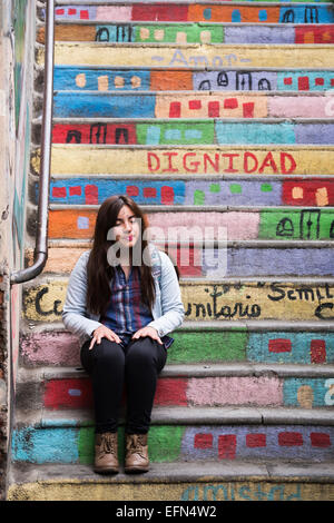 Stanco donna si siede a riposare sulle scale colorate in esecuzione tra ripide strade accanto a una funicolare in Cerro concepimento Foto Stock
