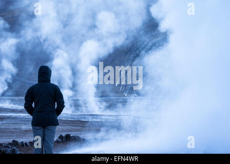 Silhouette di una persona in piedi vicino a vapore da El Tatio Geyser campo all'alba, San Pedro de Atracama, Cile Foto Stock