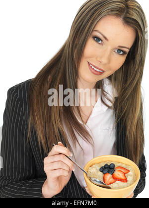 Giovani attraenti business donna mangiare una tazza di porridge con frutta fresca Foto Stock