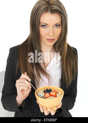 Giovani attraenti business donna mangiare una tazza di porridge con frutta fresca Foto Stock