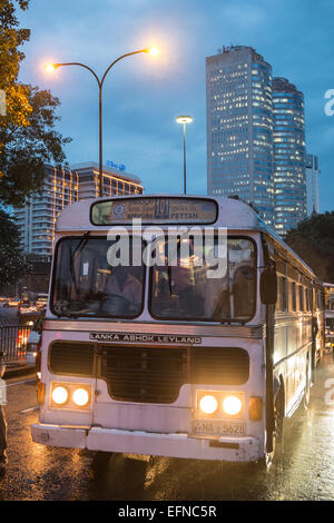 Al calar del sole,crepuscolo,locali vecchio Ashok-Leyland bus e torre di uffici di blocchi in zona centrale,Colombo Sri Lanka,Asia del Sud,Asia Foto Stock