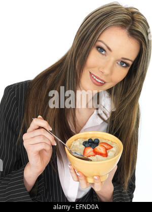 Giovani attraenti business donna mangiare una tazza di porridge con frutta fresca Foto Stock