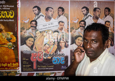 Uomo al cellulare passando in stile Bollywood cinema poster sulla parete nel centro di Colombo, Sri Lanka,Asia Foto Stock