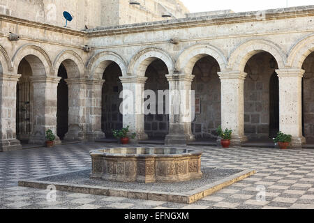 Patio con fontana circondata da un arco fatto di sillar (roccia vulcanica) nei chiostri della società in Arequipa, Perù Foto Stock