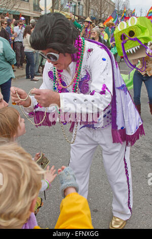 Un colorato costume Elvis dà Mardi Gras perle per bambini nella primavera del Mardi Gras Parade in downtown Asheville, NC Foto Stock