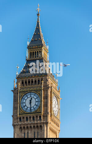 Un aereo pases dietro il Queen Elizabeth Tower, meglio conosciuto come Big Ben, un iconico punto di riferimento di Londra Foto Stock