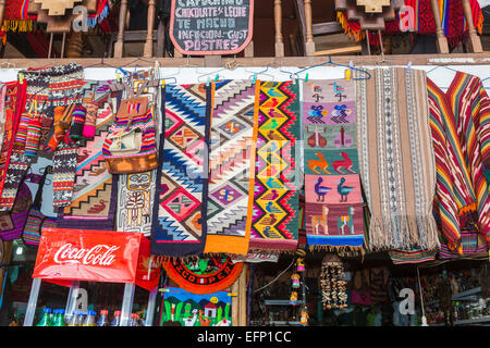 Tessuti dai colori vivaci, tessuti, tappeti e stuoie per la vendita in un negozio in un mercato a Agua Calientes, vicino a Machu Picchu, Cusco, Perù Foto Stock